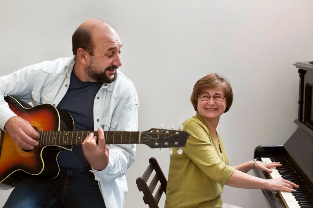 A man with a guitar and a woman at the piano in guitar lessons