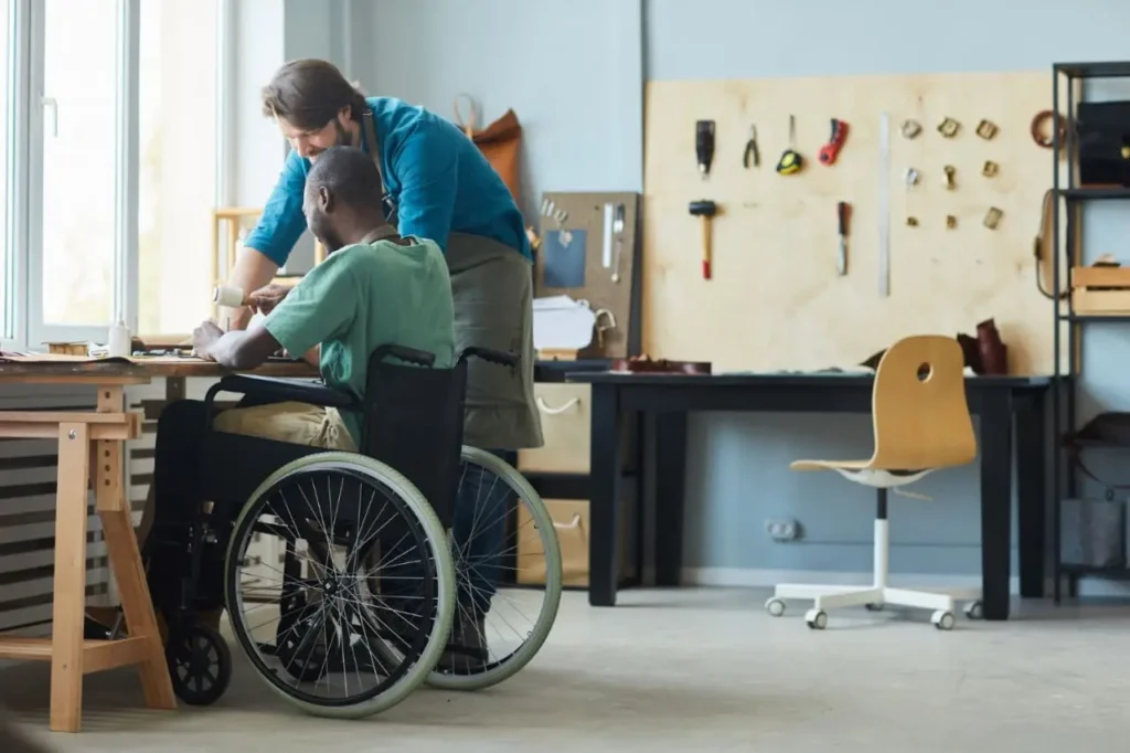 Man in wheelchair working on woodworking project in craft workshop with tool wall, participating in Acals upcycle and recycle woodworking program for NDIS participants Sydney